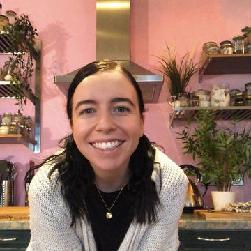 Photograph of Ashlea Cromby smiling in a kitchen with lots of houseplants behind her